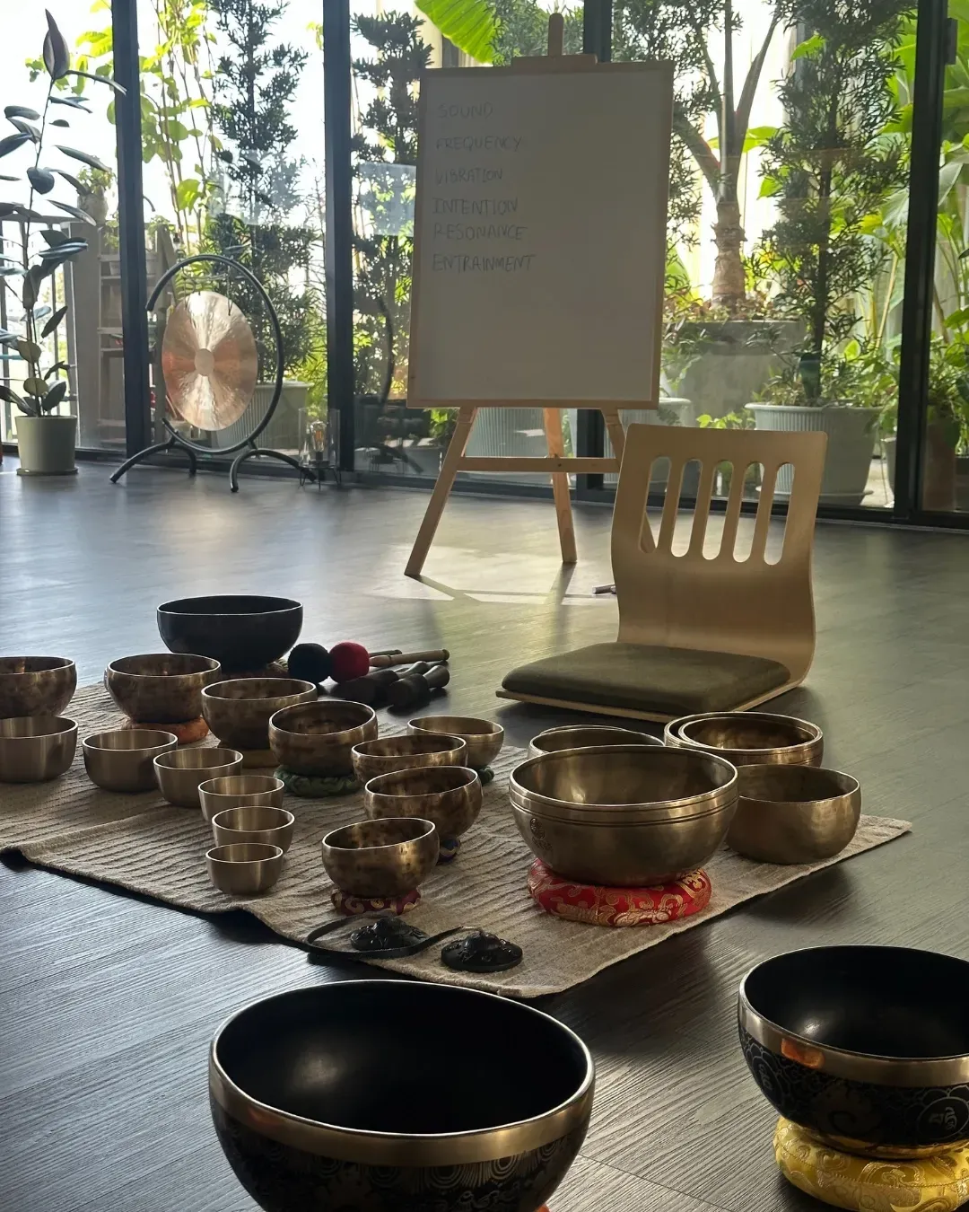 Himalayan singing bowls laid out for a workshop at Attuned Studio, with the lesson board behind.
