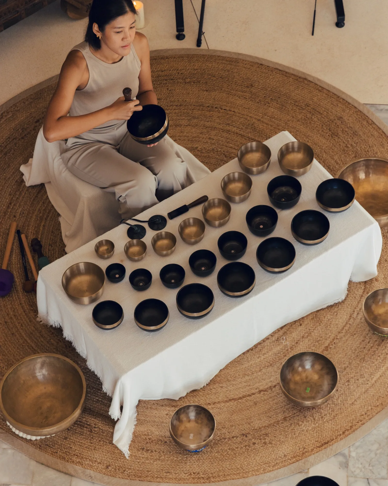 Overhead view of Ice playing a singing bowl beside a table of bowls.
