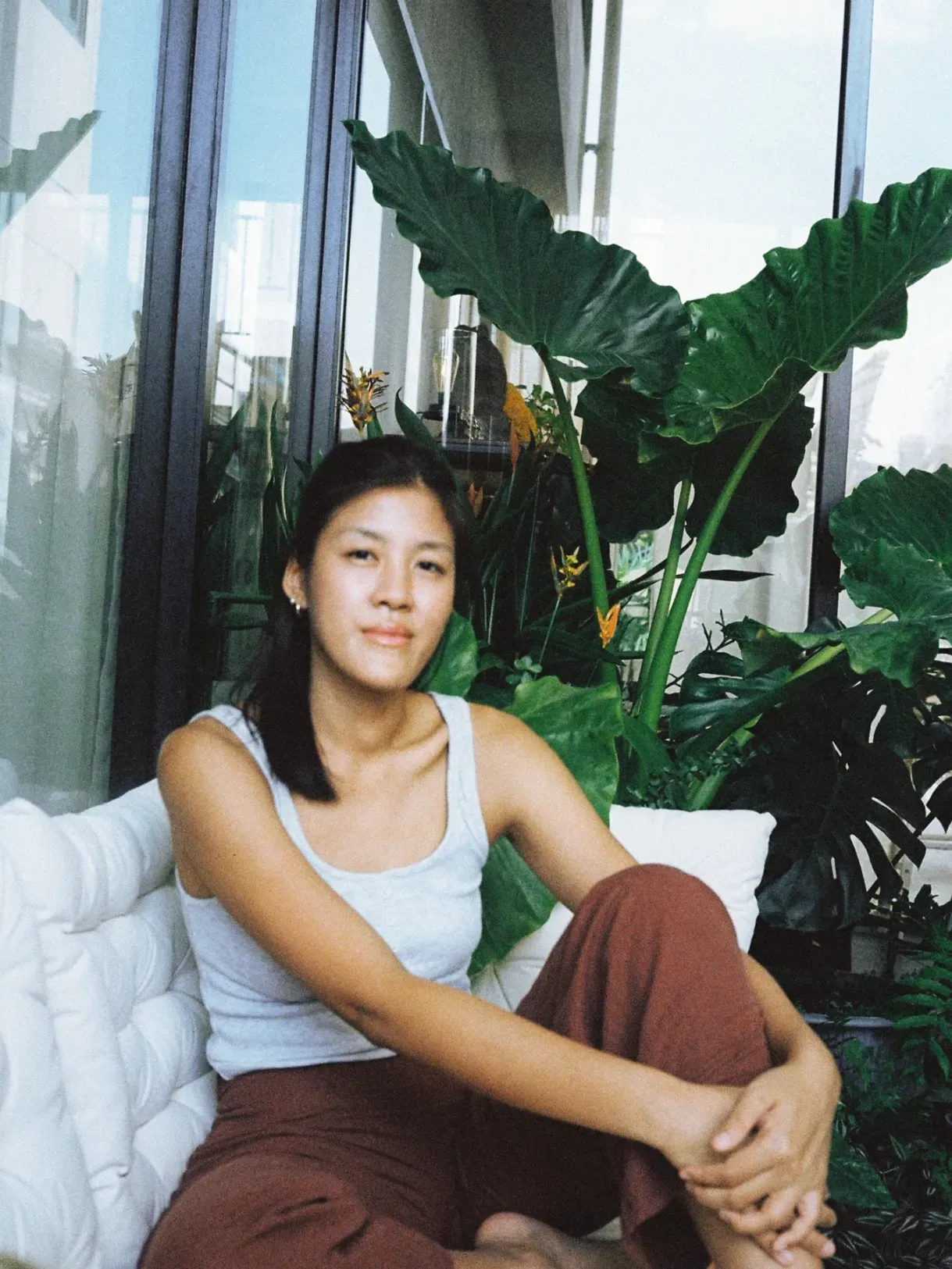 Ice, founder of Ice Sound Healing, seated among plants at home in Bangkok.